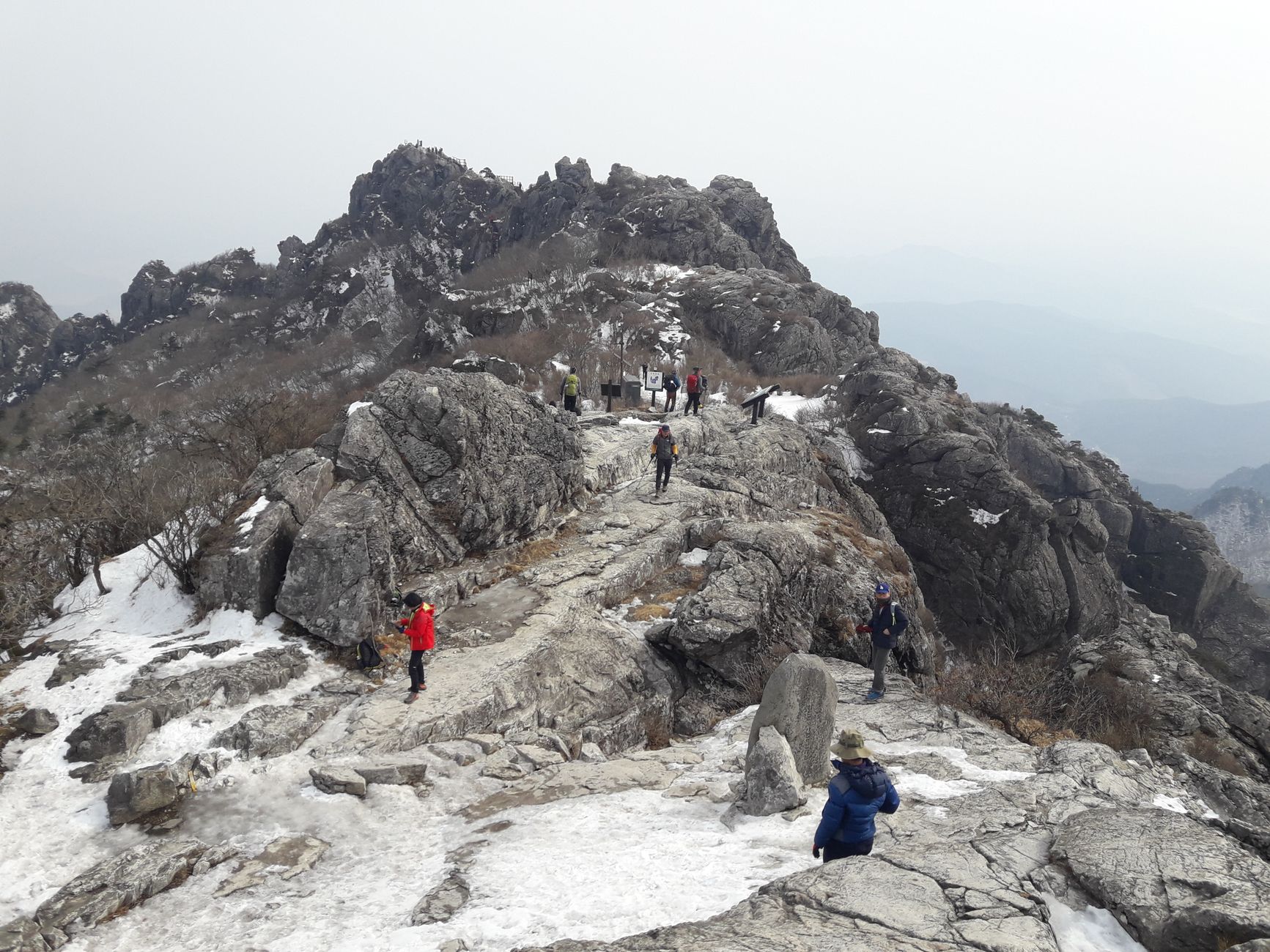 Adventurers hiking on a rocky, snow-covered mountain in Hapcheon, South Korea.