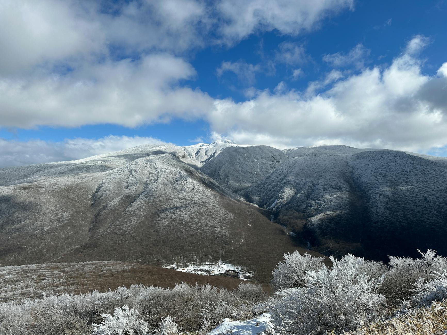 A breathtaking view of snow-covered hills under a bright winter sky in Jeju, South Korea.