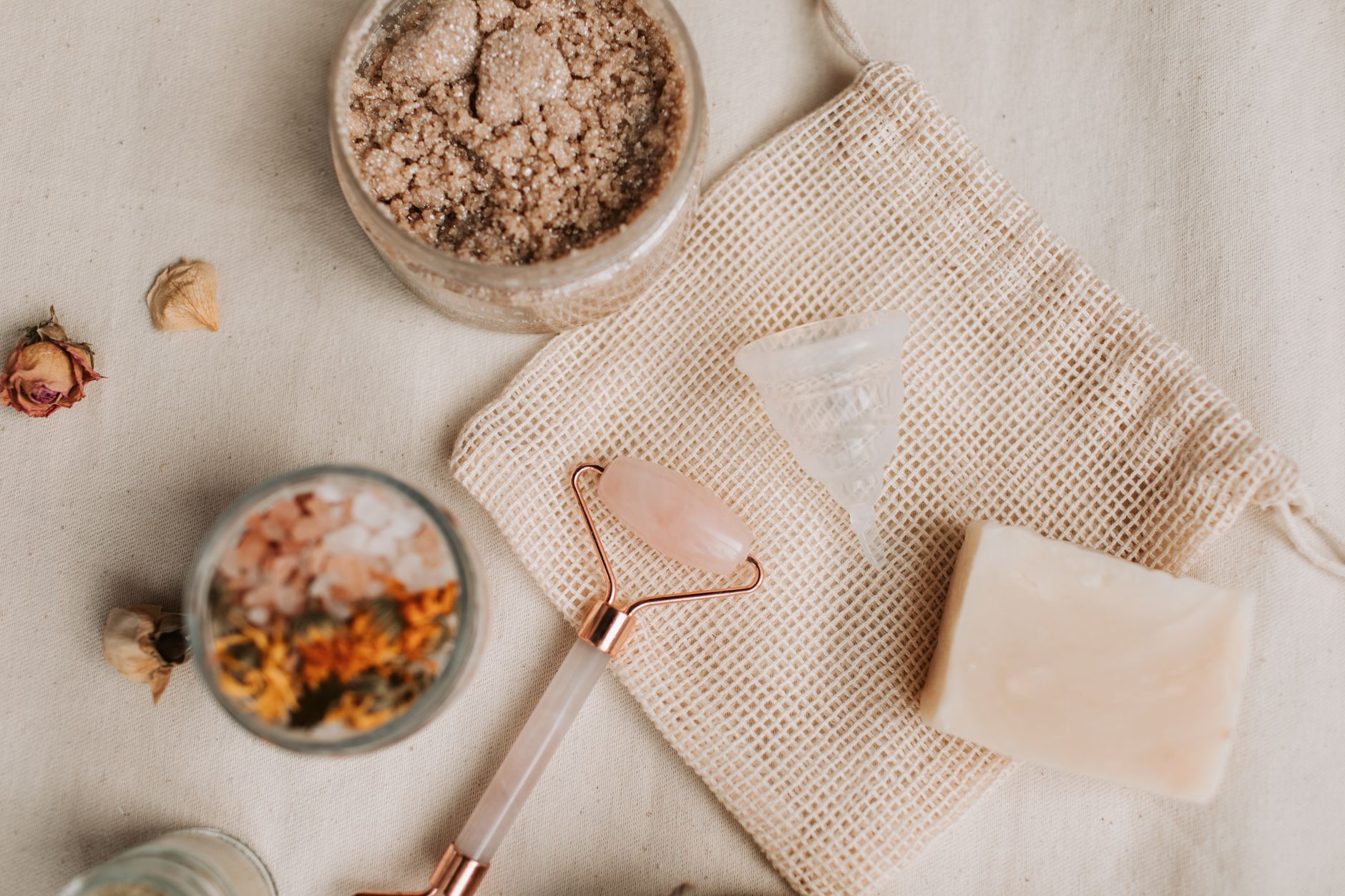 Aesthetic flat lay of natural skincare products including a jade roller and sugar scrub.