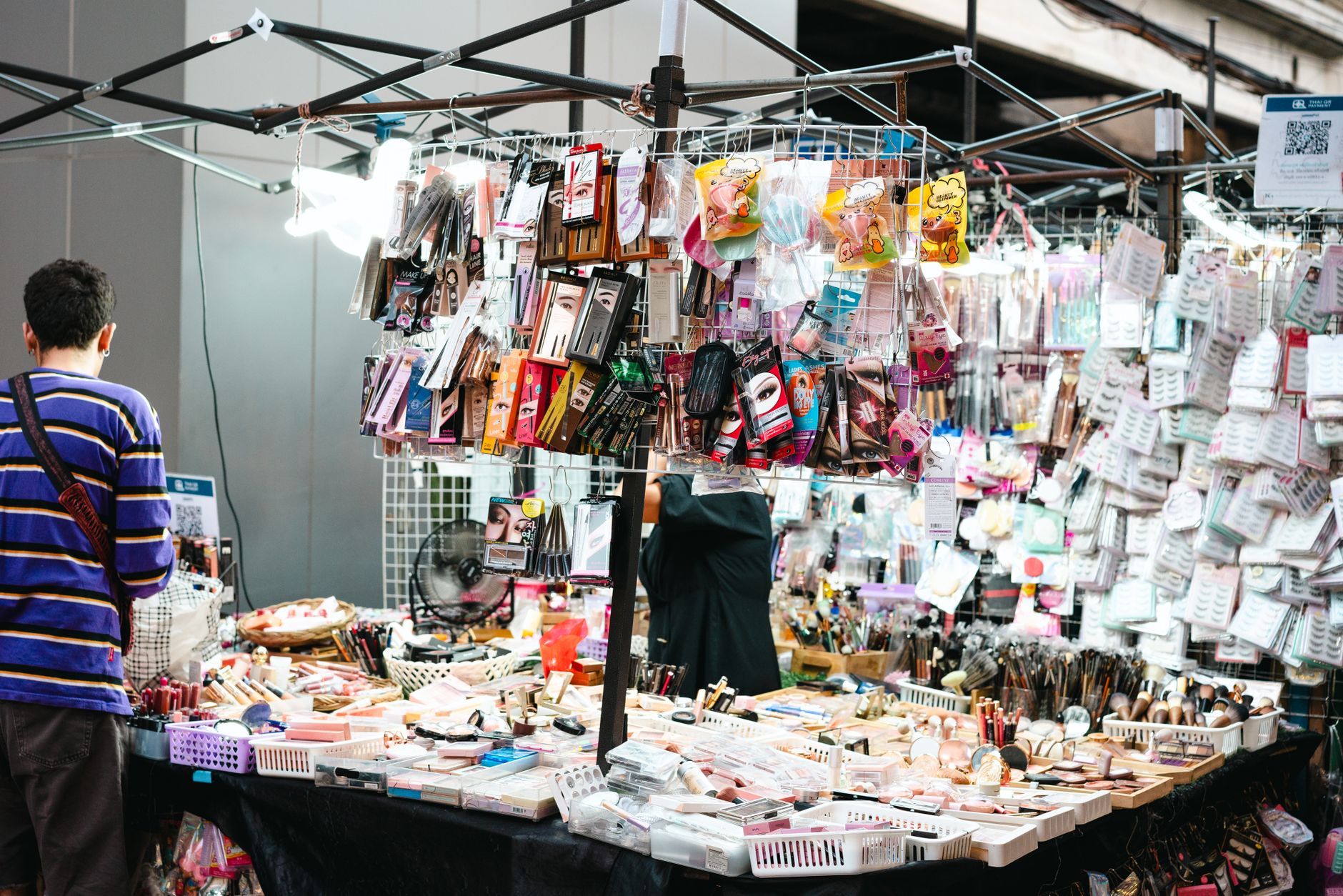A vibrant market stall displaying a variety of cosmetics and makeup items for sale.
