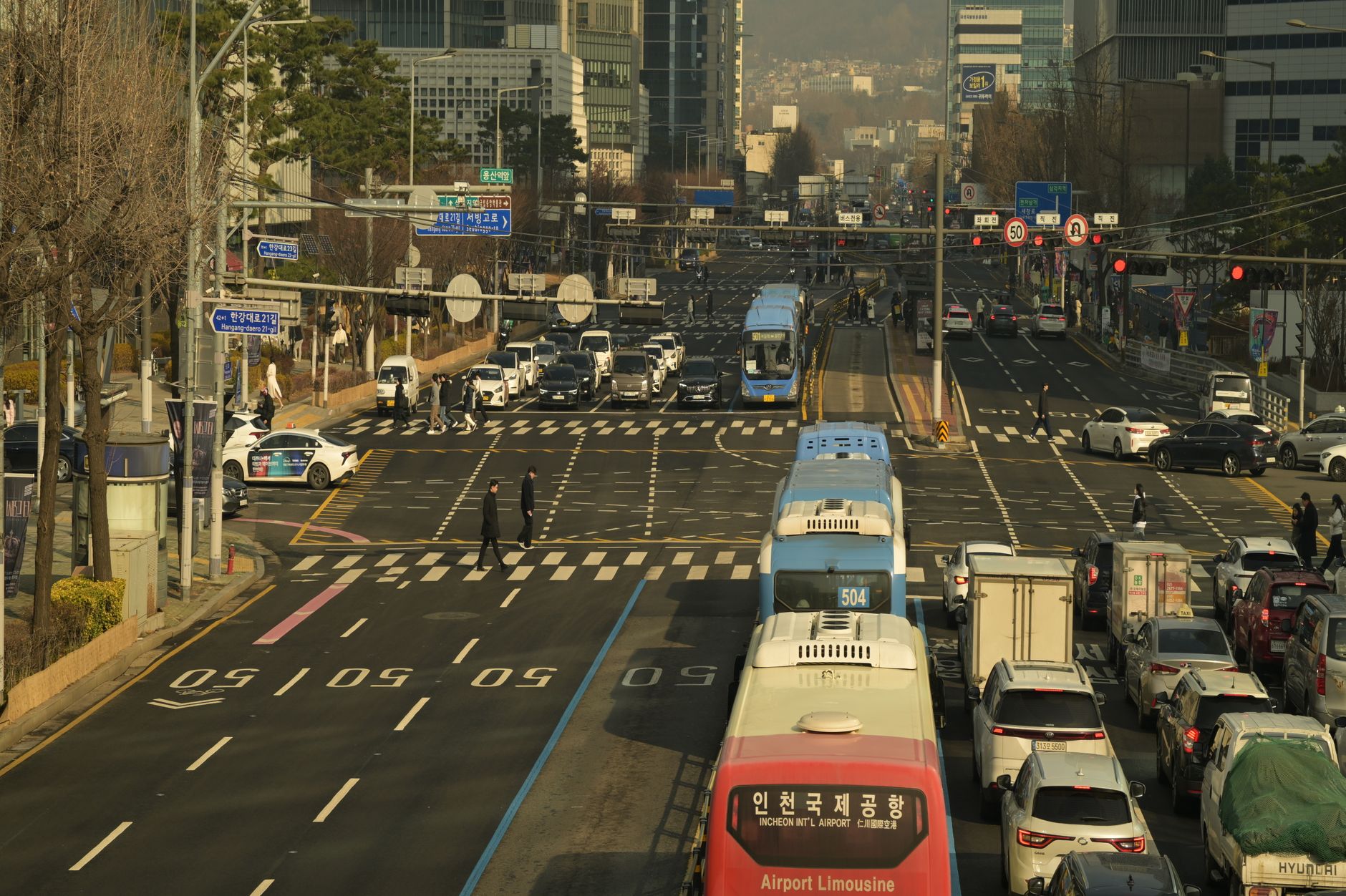 A bustling street scene in downtown Seoul, South Korea, featuring buses, cars, and pedestrians.