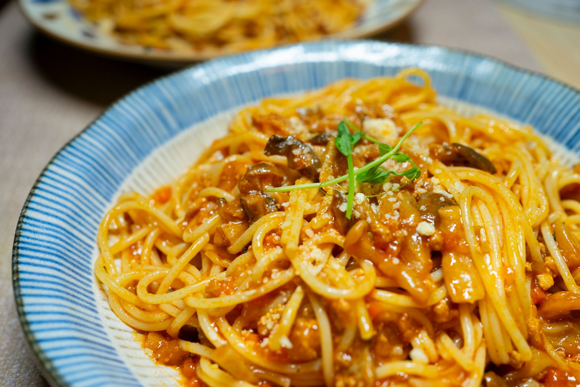 Close-up of a delicious spaghetti dish in tomato sauce with mushrooms and herbs, served in Tokyo.