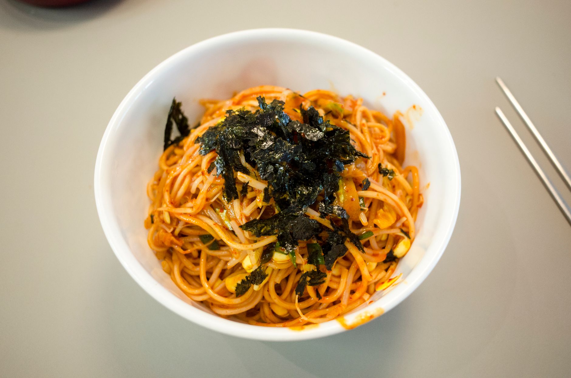Tasty Asian noodle dish garnished with nori, served in a white bowl. Perfect for a flavorful meal.