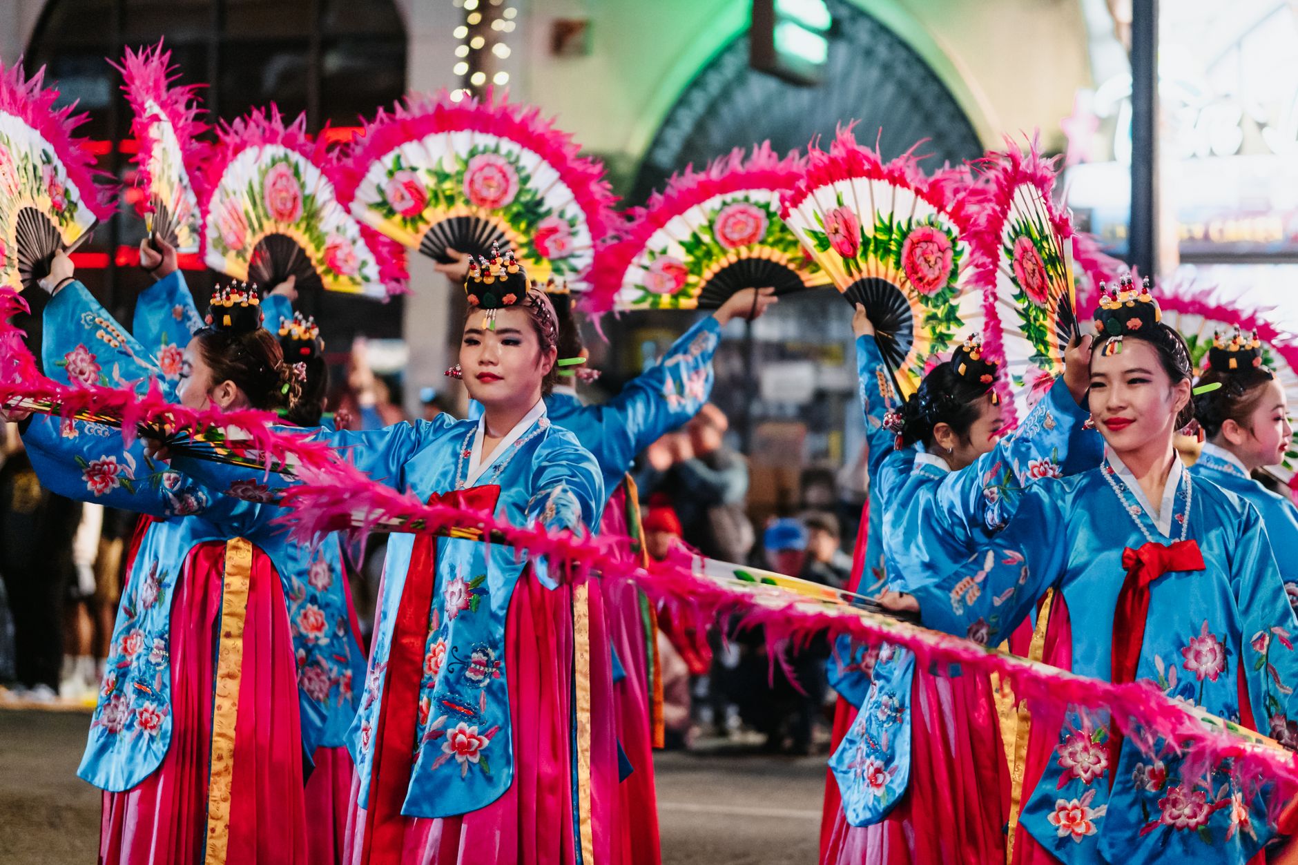 Colorful celebration featuring Asian women in traditional costumes dancing outdoors.