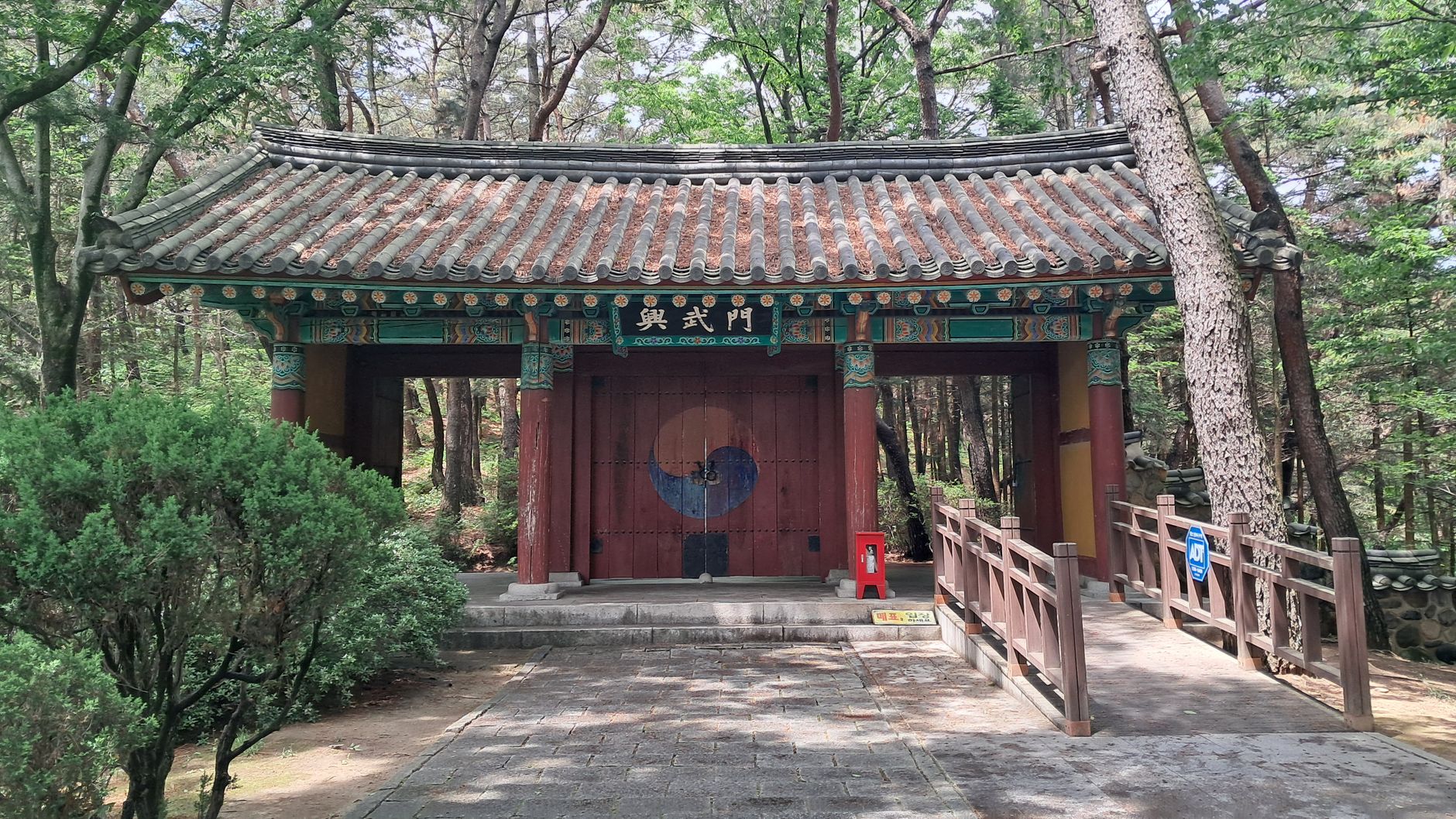 Explore the serene beauty of a traditional Korean temple gate surrounded by lush greenery in Gyeongju.