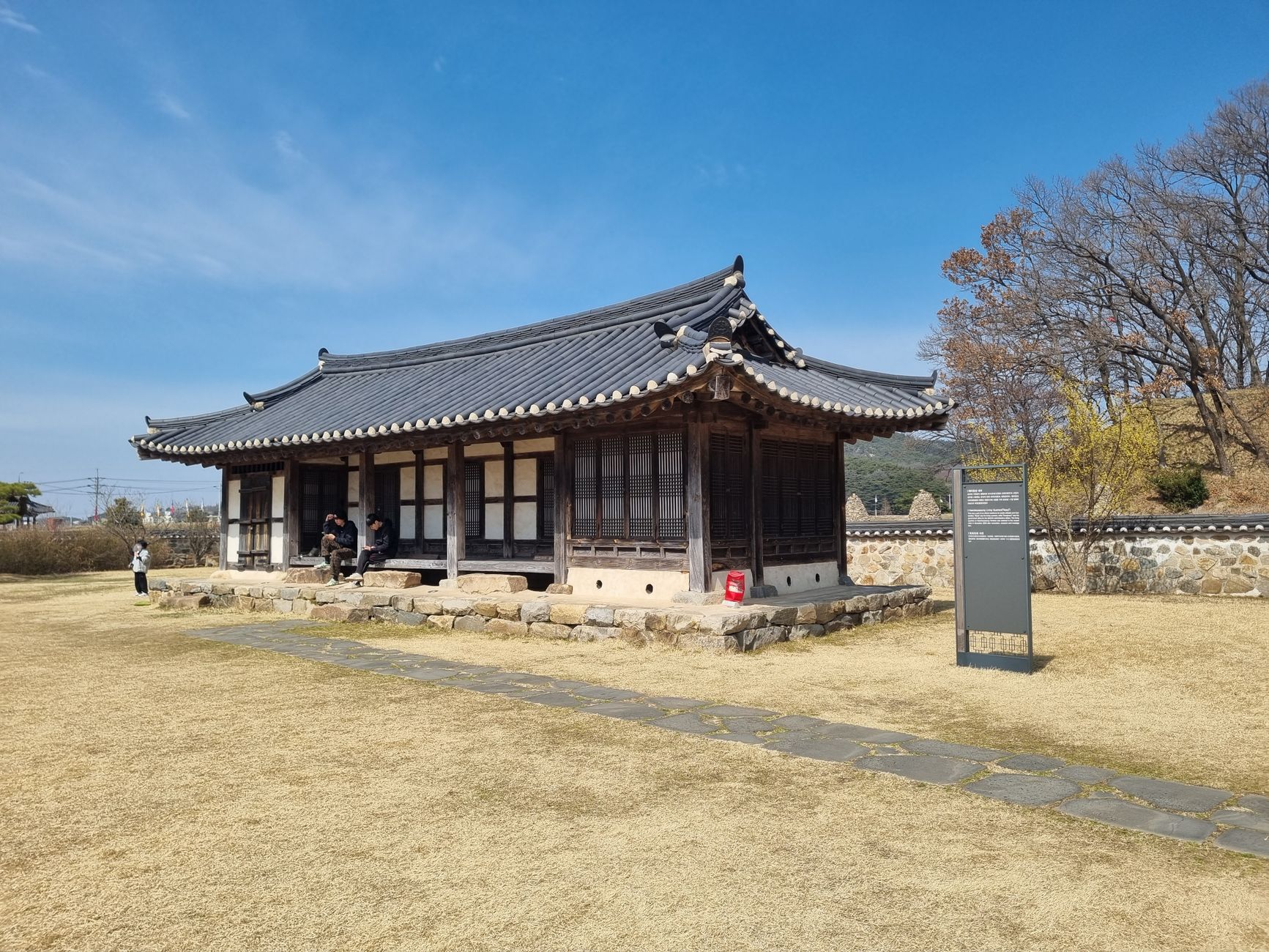 A traditional Korean Hanok structure surrounded by autumn scenery and blue skies.