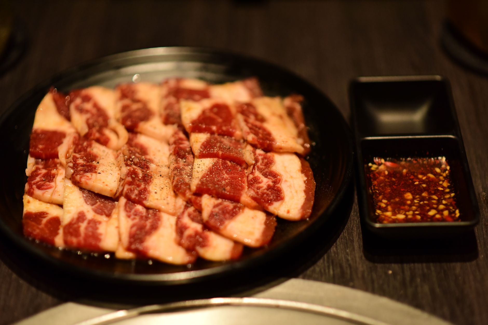 Juicy marbled beef slices with a rich seasoning sauce, ready for grilling.