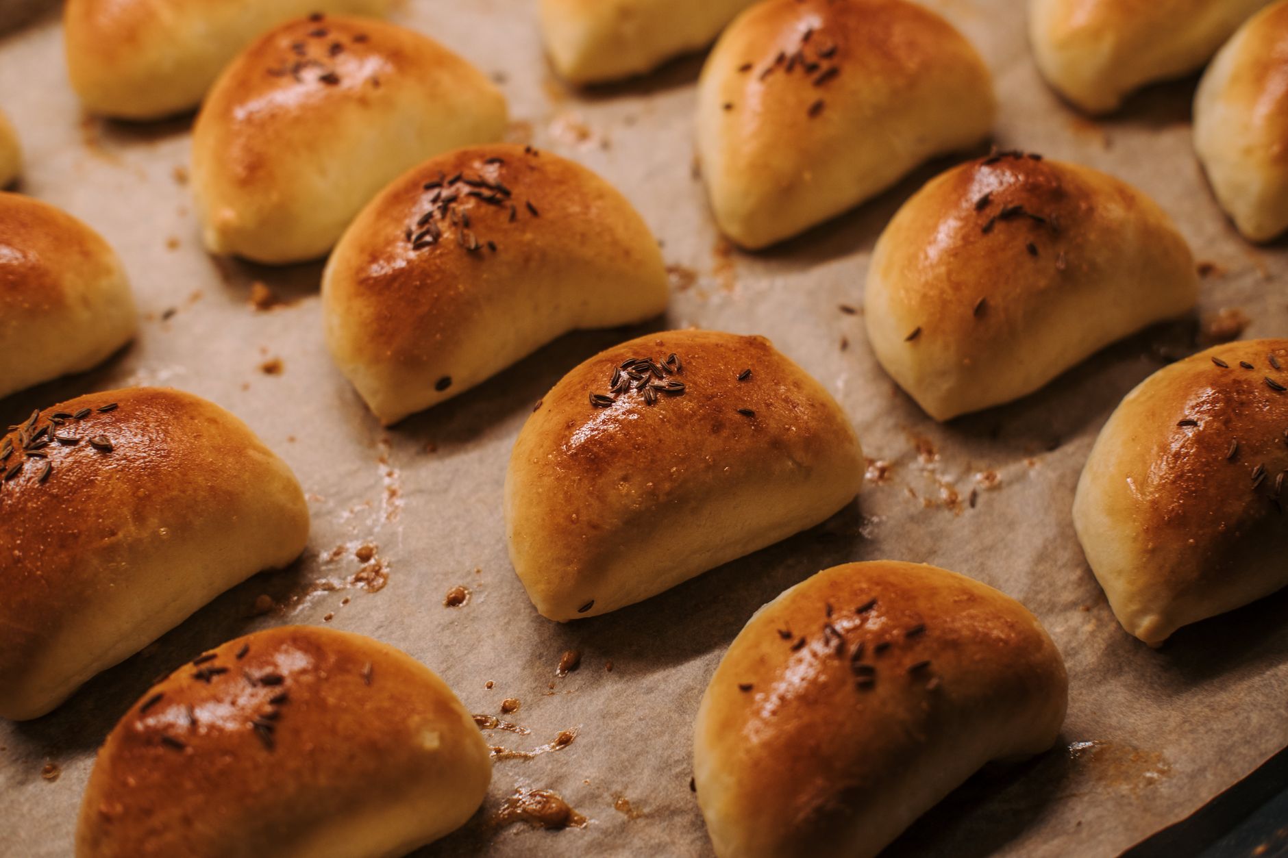 Delicious homemade dinner rolls with seeds on a baking tray, perfect for meals.