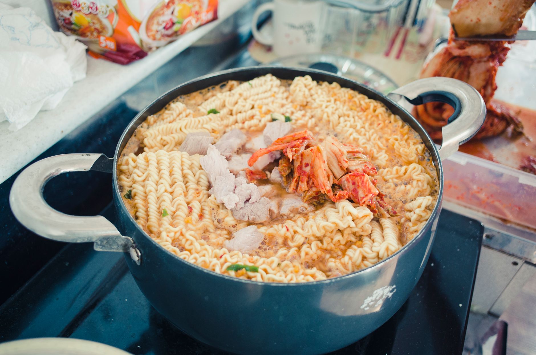 Delicious kimchi noodle soup simmering in a pot, featuring vibrant noodles and savory ingredients.