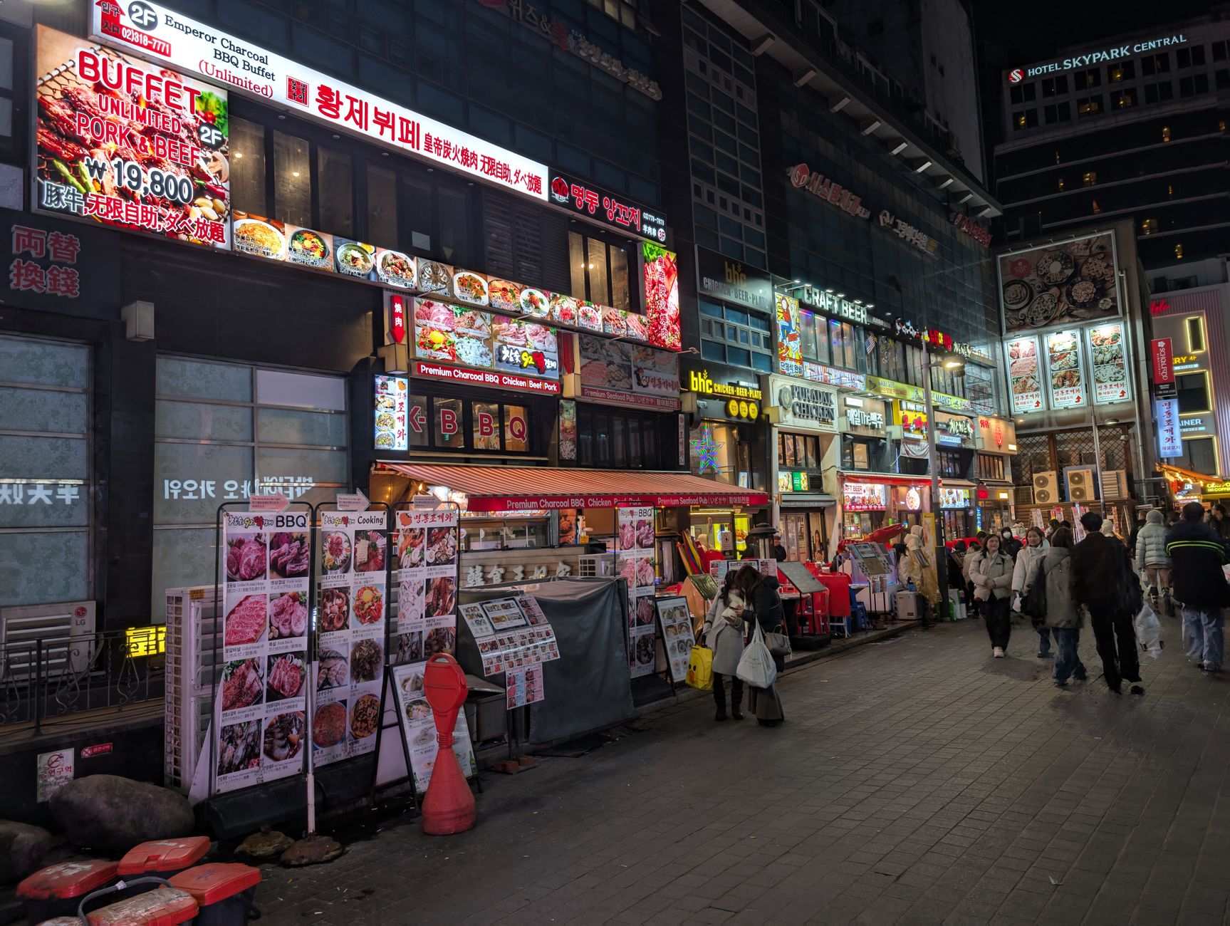 Vibrant street view in Seoul featuring various restaurants and colorful night market signs.