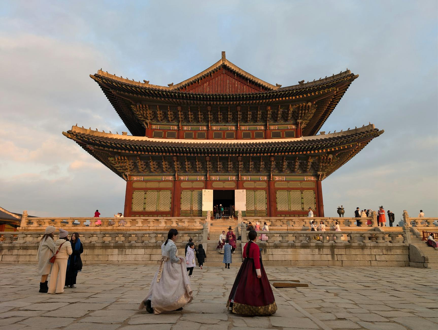 Visitors in Hanbok at Gyeongbokgung Palace, Seoul, during sunset capturing Korean culture and architecture.