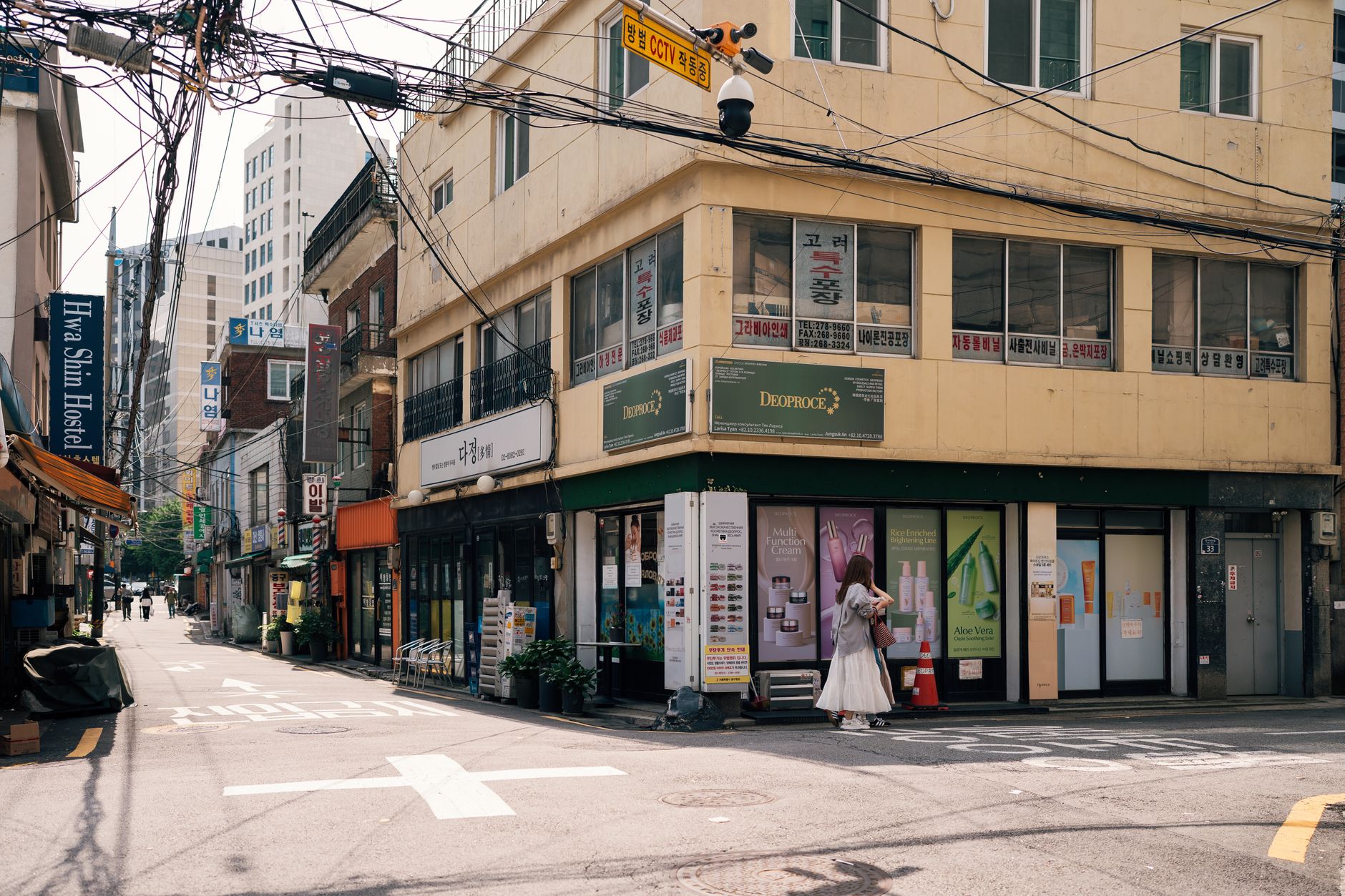 View of a street corner in Seoul, featuring urban architecture and a pedestrian under sunny weather.