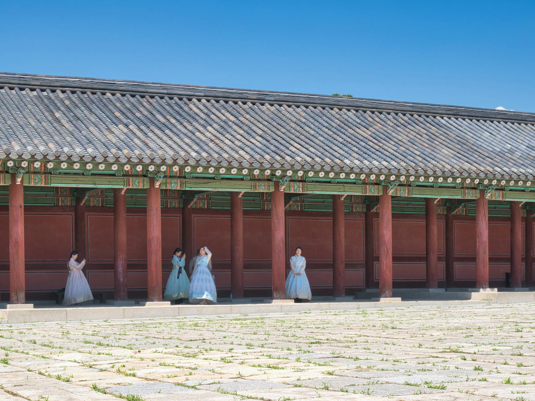 Women in traditional Korean hanbok stand by a historical palace in Seoul, showcasing cultural heritage.