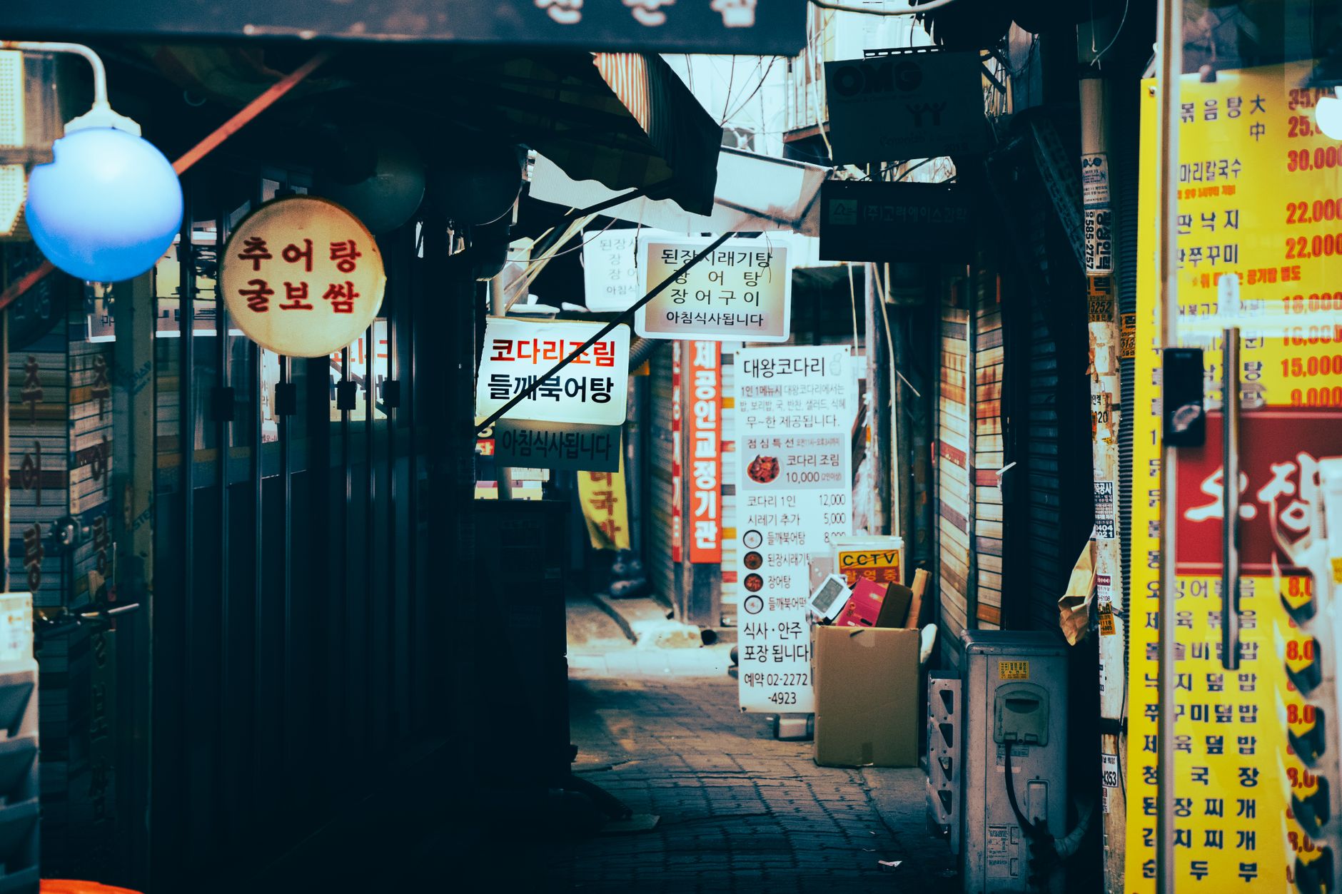 Vibrant narrow alley filled with colorful signs and bustling market atmosphere.